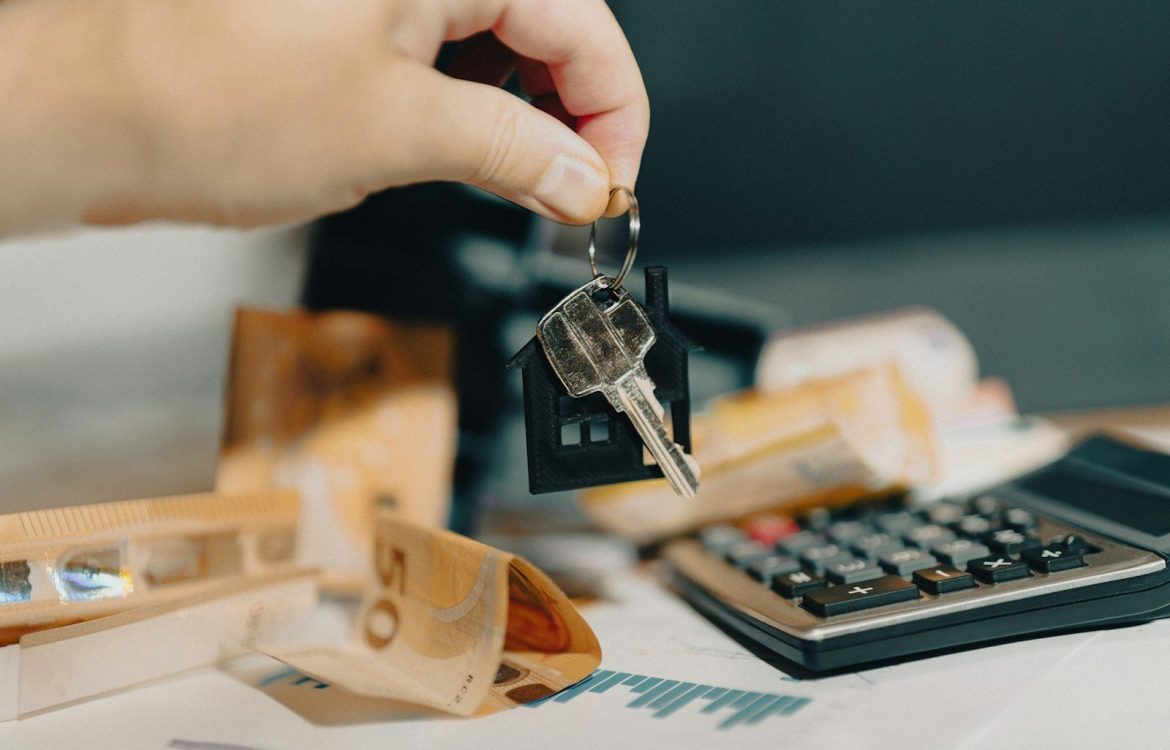 A person holding a house key in front of a calculator